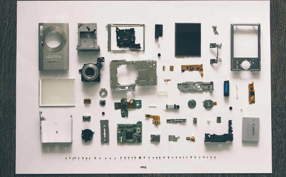A camera disassembled into its component parts, laid out in a grid